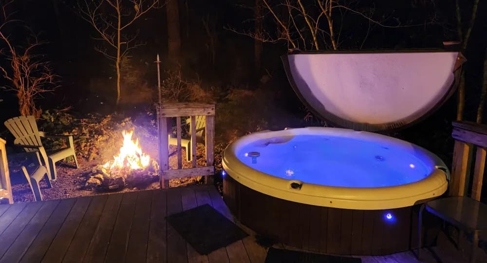 An inviting hot tub beside a softly lit outdoor seating area at dusk